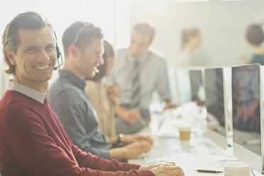 Portrait smiling telemarketer talking on telephone with headset at computer - CAIF10432