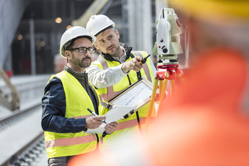 Männliche Ingenieure benutzen einen Theodolit auf einer Baustelle - CAIF10444