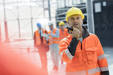 Male foreman using walkie-talkie at construction site - CAIF10448