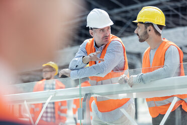 Männlicher Polier und Bauarbeiter unterhalten sich auf der Baustelle - CAIF10454