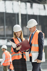 Architects reviewing paperwork at construction site - CAIF10460