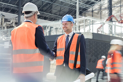 Männliche Ingenieure beim Händeschütteln auf der Baustelle - CAIF10461