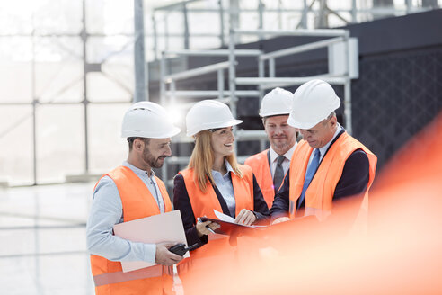 Vorarbeiter und Ingenieure besprechen auf der Baustelle den Papierkram - CAIF10462