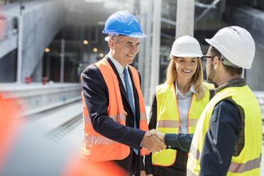 Geschäftsmann und Ingenieur beim Händeschütteln auf der Baustelle - CAIF10463