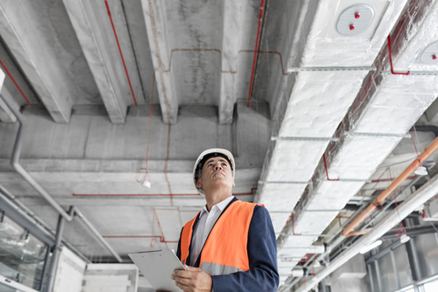 Foreman with clipboard looking up at construction site stock photo