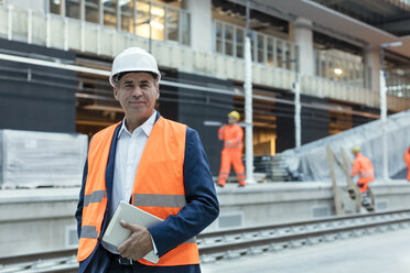 Porträt eines selbstbewussten Ingenieurs mit digitalem Tablet auf einer Baustelle - CAIF10480