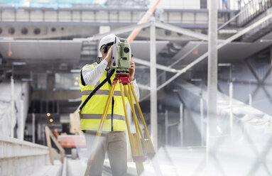 Männlicher Ingenieur mit Theodolit auf einer Baustelle - CAIF10482