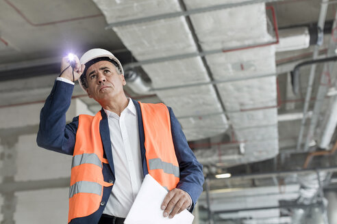 Vorarbeiter mit Taschenlampe auf Bauarbeiter - CAIF10487