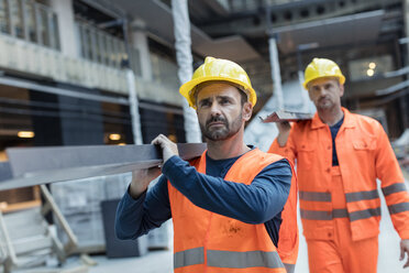 Bauarbeiter tragen Metall auf einer Baustelle - CAIF10491