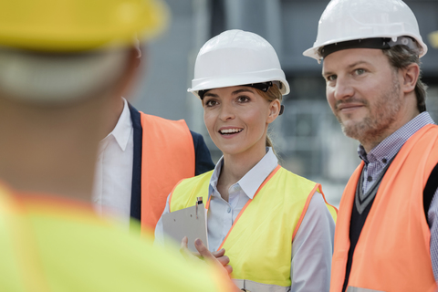 Lächelnde Ingenieure treffen sich auf der Baustelle, lizenzfreies Stockfoto