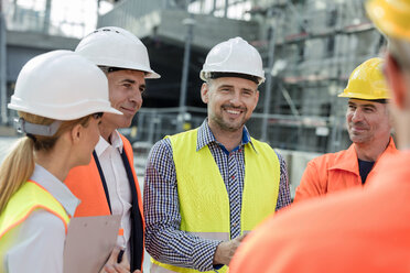 Lächelnde Ingenieure und Bauarbeiter treffen sich auf der Baustelle - CAIF10495