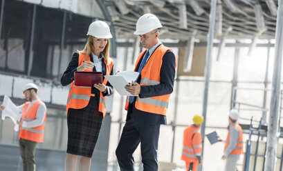 Ingenieure mit Klemmbrettern treffen sich auf der Baustelle - CAIF10496