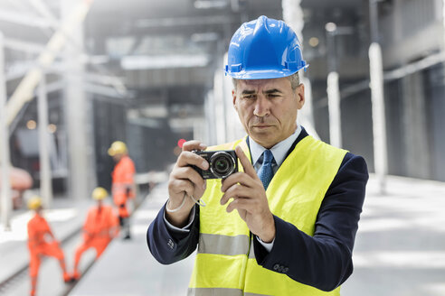 Geschäftsmann mit Digitalkamera auf einer Baustelle - CAIF10500