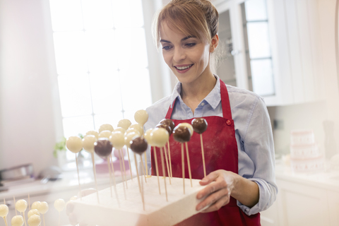 Lächelnde Catererin beim Backen von Cake Pops in der Küche, lizenzfreies Stockfoto