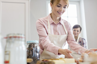 Lächelnde Frau beim Backen in der Küche - CAIF10511