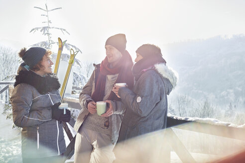 Skier friends talking, drinking coffee and hot cocoa apres-ski - CAIF10531