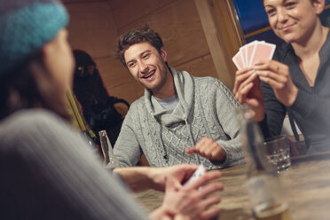 Freunde spielen Karten am Tisch in der Hütte - CAIF10534