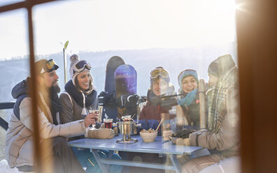 Snowboarderfreunde trinken und essen am Balkontisch beim Après-Ski - CAIF10537