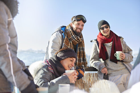 Smiling skier friends drinking coffee and hot cocoa outside apres-ski - CAIF10539