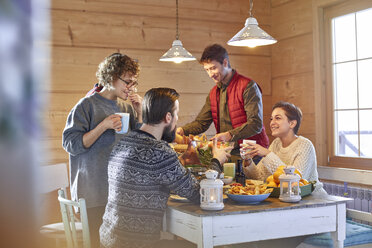 Friends eating and talking at cabin table - CAIF10548