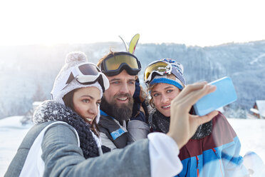 Skifreunde machen ein Selfie mit einem Fotohandy auf einem verschneiten Feld - CAIF10562