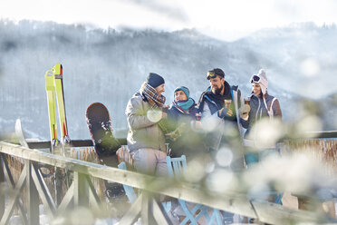 Skifreunde unterhalten sich und trinken Cocktails auf dem sonnigen Balkon beim Après-Ski - CAIF10569