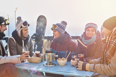 Snowboarder-Freunde trinken Cocktails auf dem sonnigen Balkon beim Après-Ski - CAIF10571