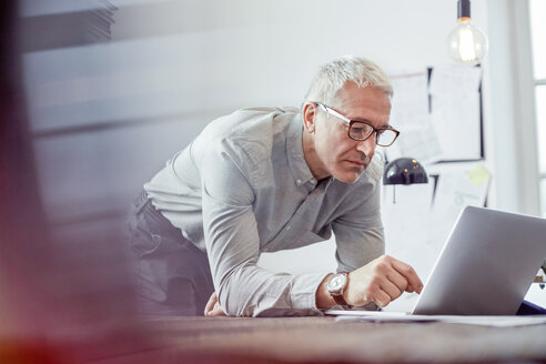 Ernster, konzentrierter Geschäftsmann, der im Büro am Laptop arbeitet - CAIF10586