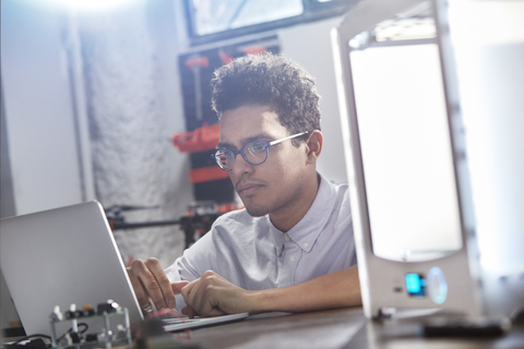 Fokussierter junger männlicher Designer mit Laptop, lizenzfreies Stockfoto