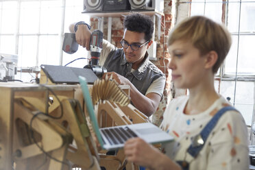 Designer mit Laptop und Bohrmaschine in der Werkstatt - CAIF10610