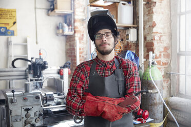 Portrait confident welder with welding torch in workshop - CAIF10612