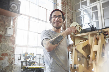 Männlicher Designer mit Tattoos bei der Arbeit an einem Prototyp in einer Werkstatt - CAIF10620