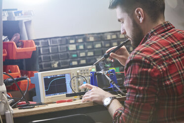 Männlicher Ingenieur beim Zusammenbau von Elektronik, mit Lötkolben - CAIF10633