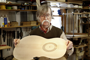 Mann fertigt Gitarre in einer Werkstatt - CAVF05301