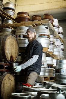 Portrait of man removing beer from barrel at brewery - CAVF05336