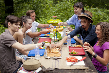 Freunde beim Frühstück an einem Picknicktisch im Wald - CAVF05415