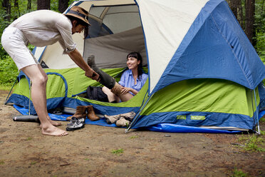 Mann entfernt den Stiefel einer Frau auf einem Campingplatz - CAVF05427