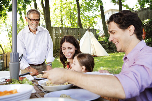 Familie genießt das Essen auf der Wiese - CAVF05435