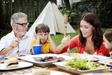 Familie beim Essen am Tisch im Garten - CAVF05436