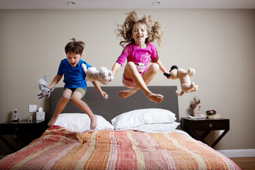 Verspielte Kinder, die zu Hause auf dem Bett herumspringen - CAVF05438