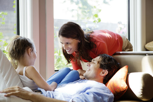 Eltern schauen Mädchen an, während sie zu Hause auf dem Sofa sitzen - CAVF05446