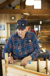 Älterer Mann arbeitet in der Werkstatt an einem Kanu - CAVF05455