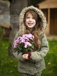 Mädchen trägt Topfpflanze, während sie im Hinterhof steht - CAVF05557
