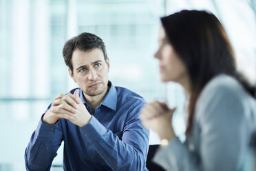 Attentive serious businessman listening to businesswoman in meeting - CAIF10677