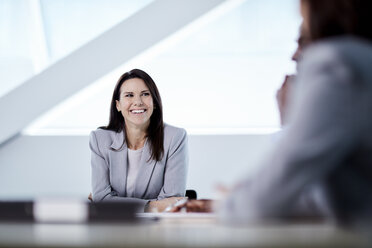 Lächelnde Geschäftsfrau hört in einer Besprechung zu - CAIF10681