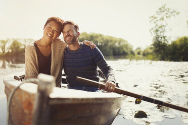 Portrait hugging couple canoeing on sunny lake - CAIF10707