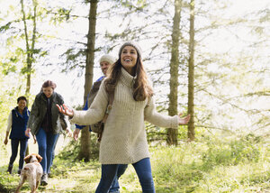 Lächelnde Frau beim Wandern mit Freunden im Wald - CAIF10715