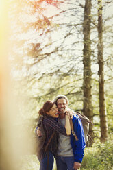 Portrait enthusiastic couple with backpacks hiking in sunny woods - CAIF10716