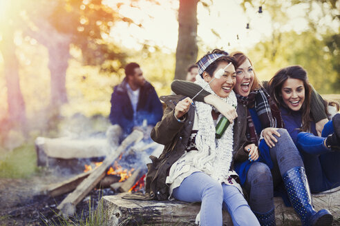 Lachende Freunde beim Rösten von Marshmallows am Lagerfeuer - CAIF10717