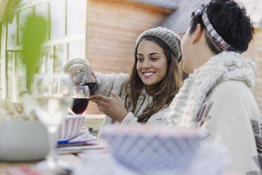 Freunde schenken am Mittagstisch auf der Terrasse Wein ein - CAIF10722